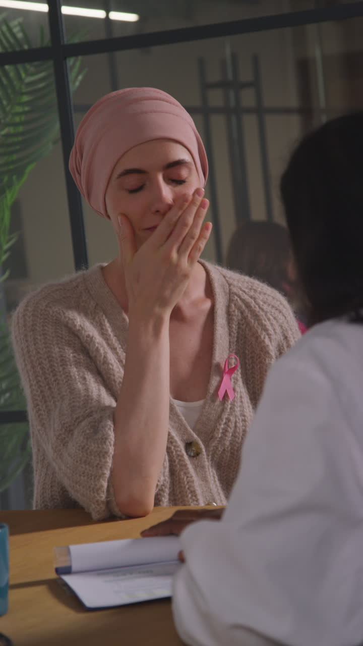 Vertical Video Of Young Woman Patient Wearing Headscarf Getting Good News At Meeting With Oncologist Or Doctor In Hospital For Breast Cancer Treatment