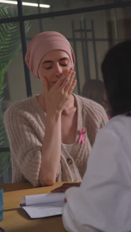 vertical video of young woman patient wearing headscarf getting good news at meeting with oncologist or doctor in hospital for breast cancer treatment