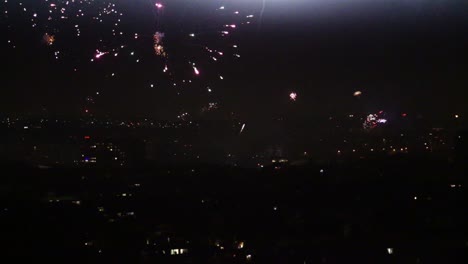 Fireworks-going-off-over-city-skyline-at-midnight-during-new-year-view-from-top-of-hill
