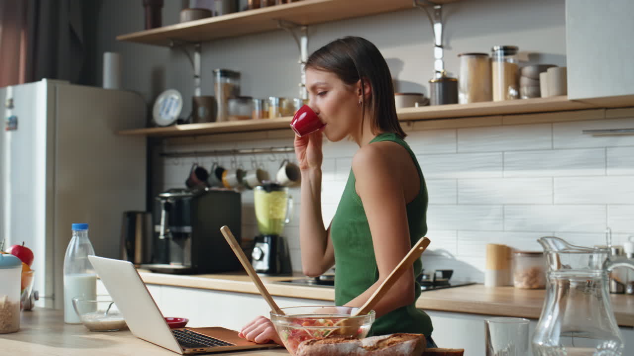 mujer que usa la computadora portátil en la cocina