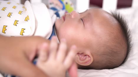 baby holding his mother's hand and sleep, video in 4k