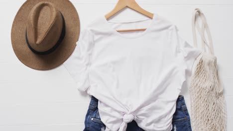 video of white t shirt, denim shorts, hat, bag and copy space on white background