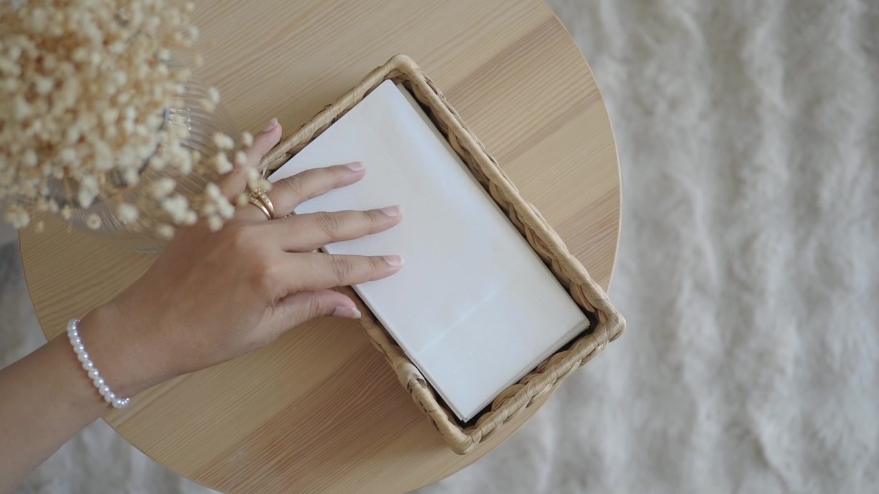 Donna che prende un tovagliolo da un cestino di vimini su un tavolo di legno