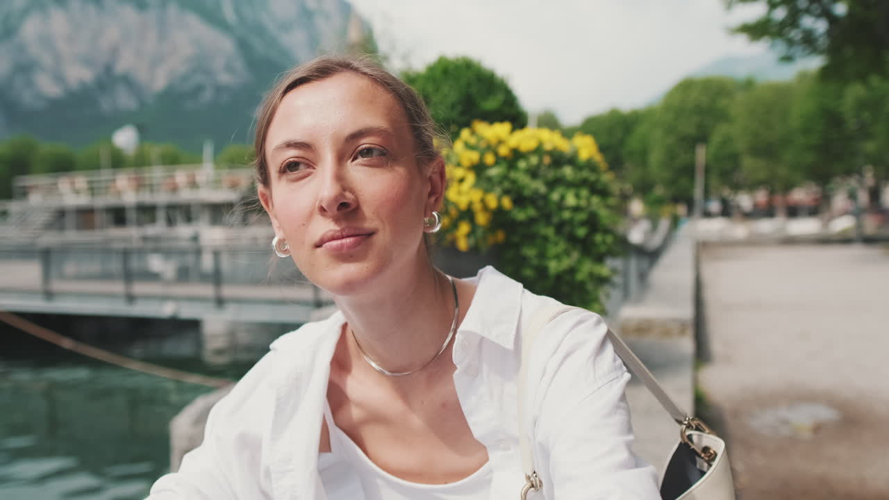Ung kvinde ser sig omkring ved en sø med bjerge
