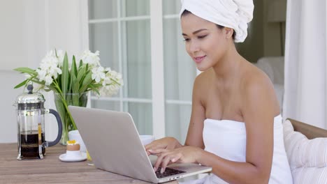 beautiful woman in bath towel using laptop