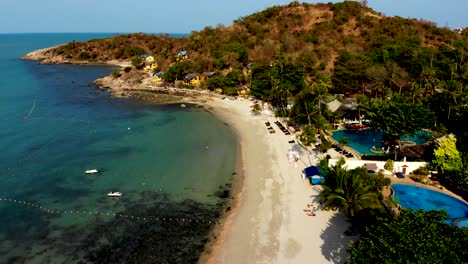 Tilting-drone-shot-of-the-coastline-of-Thongson-Bay-with-its-sandy-beach,-clear-blue-waters,-and-the-rocky,-hilly-slope-in-Koh-Samui-island-in-Thailand