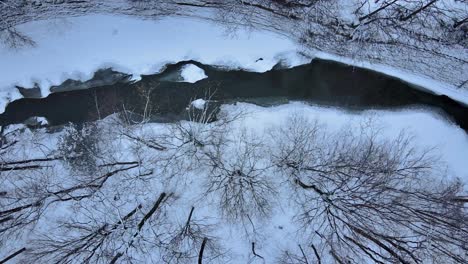 aerial drone footage of a partially frozen creek during winter in western new york state after fresh snowfall