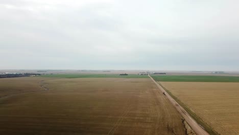 aerial reveal view of early spring of wheat field and a gravel road in rural nebraska usa