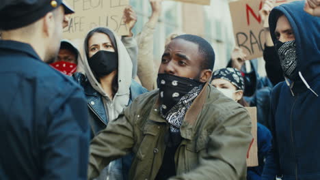 afroamerikaner schreit einen polizisten bei einem protest mit einer multiethnischen gruppe von menschen auf der straße an