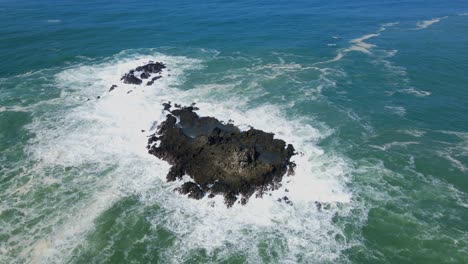 Vista-Aérea-Superior-Que-Muestra-La-Espuma-De-Las-Olas-Rompiendo-Contra-La-Roca-De-Coral-A-La-Luz-Del-Sol