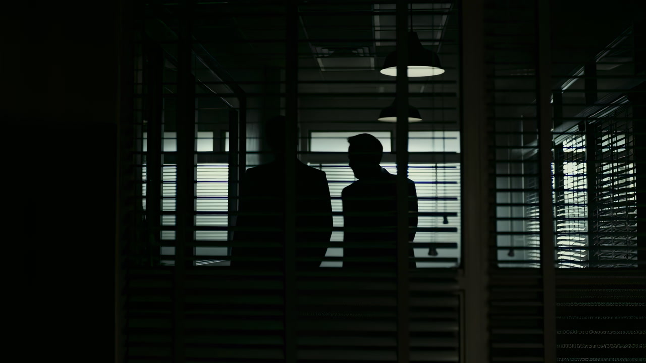 Silhouetted Executives In Dim Office, Two Figures Converse Behind Blinds, Low Lighting Creates Deep Shadows