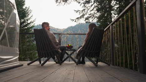 couple sitting on a deck overlooking a lake and mountains