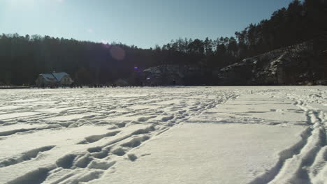 Large-frozen-Harasov-lake-imprinted-by-ice-skating-tracks-and-footprints-in-Kokorin,-Czech-Republic---Wide-slide-travelling-shot