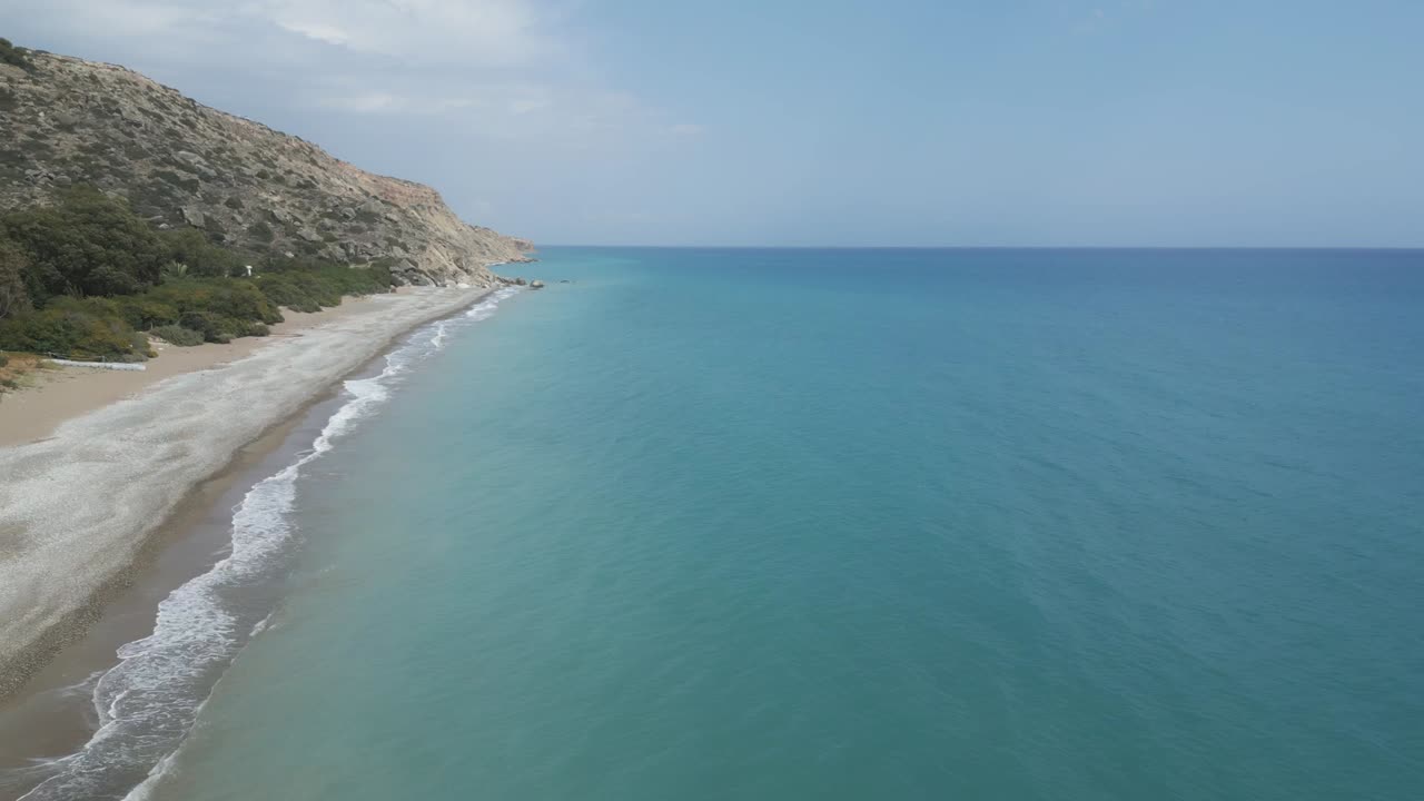 playa desierta de pissouri en chipre con olas suaves, cielo despejado, vista aérea