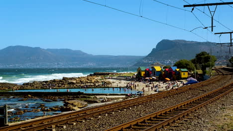 wide dolly of tourists swimming in tide pool - st james beach, colorful huts