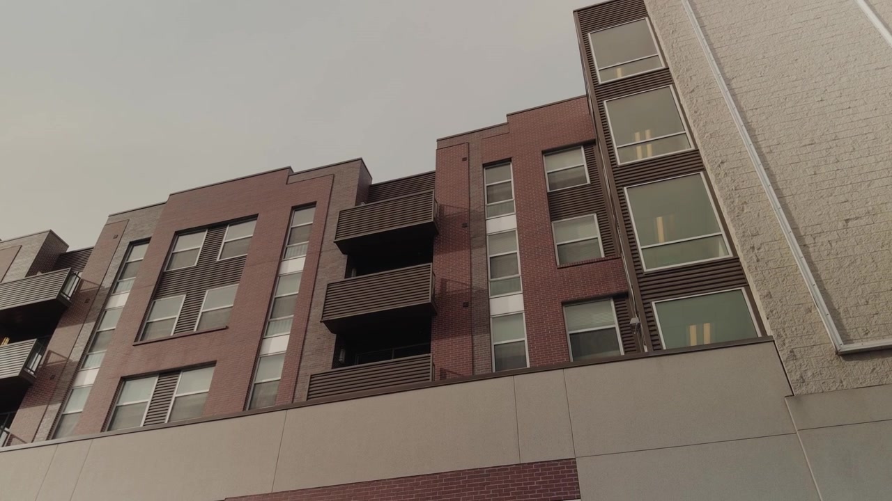 Panorámica constante de derecha a izquierda a través de un edificio residencial con fachada de ladrillo y cristal