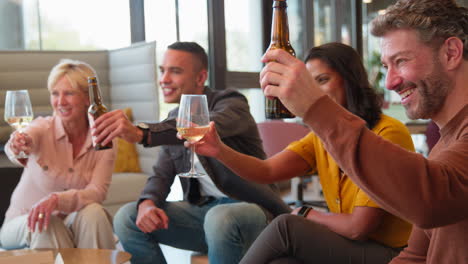 staff at informal meeting in office making a toast with drinks after work