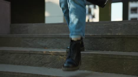 primer plano de una mujer bajando la escalera con zapatos oscuros y pantalones vaqueros en un día soleado