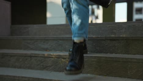 close-up of female walking down staircase with dark shoes and jeans on sunny day