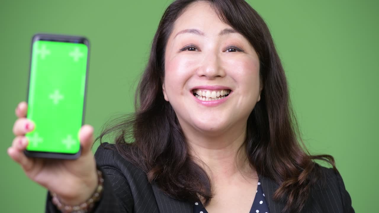 Mature beautiful Asian businesswoman showing phone