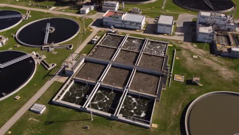 aerial view of pools of industrial water purification plant factory lighting in sunlight - buenos aires,argentina - south america -orbiting shot