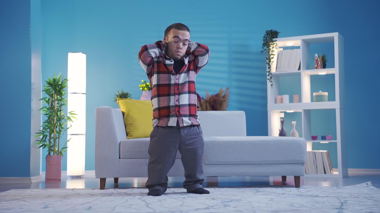 The disabled young man with dwarfism, who is alone at home, is bored and unhappy.
