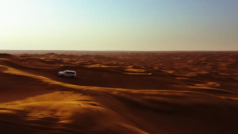 Aerial-view-of-4x4-off-road-land-vehicle-taking-tourists-on-desert-dune-bashing-safari-in-Dubai,-UAE