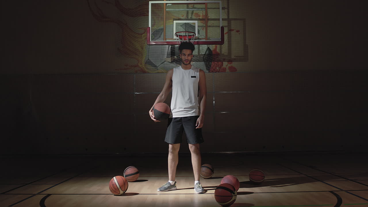 Sportsman Posing on Dark Indoor Basketball Court