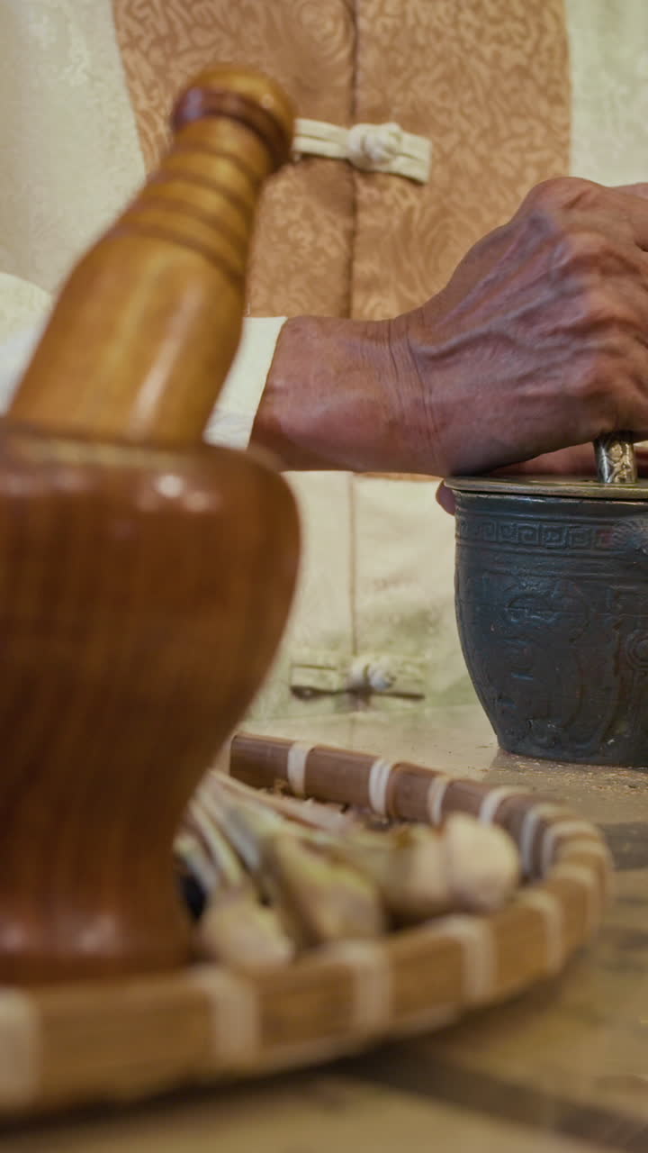 Asian Male Healer Grinding Herbs in Mortar Using Pestle