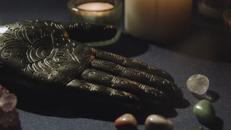 close up of model of hand used in palm reading surrounded by candles and crystals