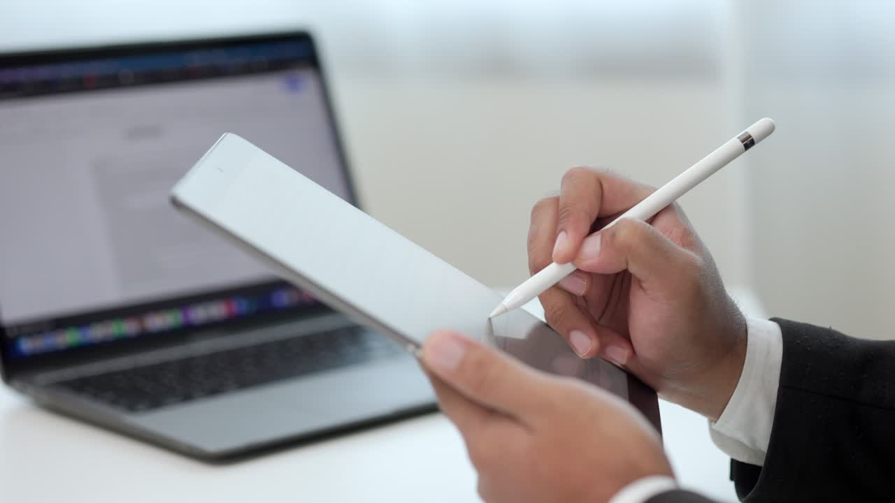 Uomo d'affari che firma un contratto con una penna stilo su un tablet digitale in ufficio. Primo piano di una mano che sigla un accordo commerciale. Firma elettronica su tablet
