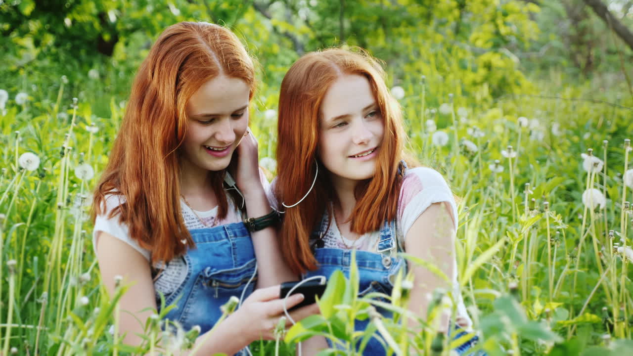 dos hermanas gemelas pelirrojas escuchan música en los auriculares 2