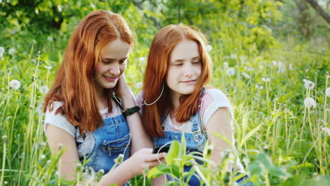 two red-haired twin sisters listen to music on headphones 2