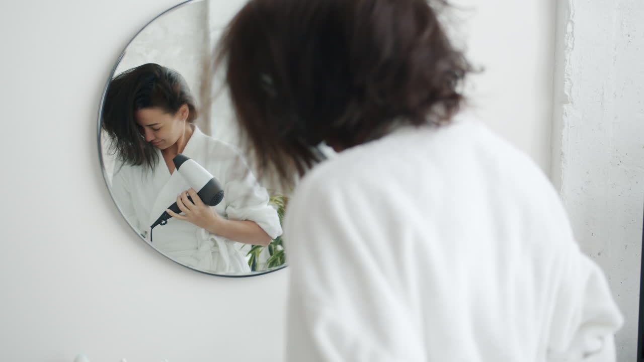 Donna che si asciuga i capelli in bagno
