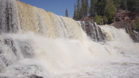 cascada rugida en cascada sobre el terreno rocoso entre el bosque