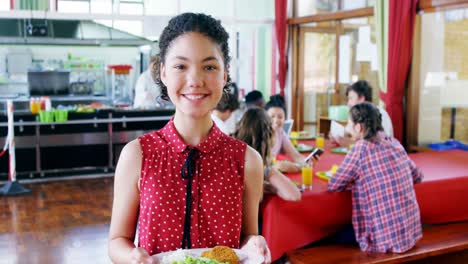 portrait of happy schoolgirl holding breakfast in plate