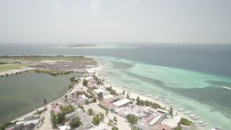 Gran-roque-with-turquoise-waters-and-boats,-sunny-day,-aerial-view