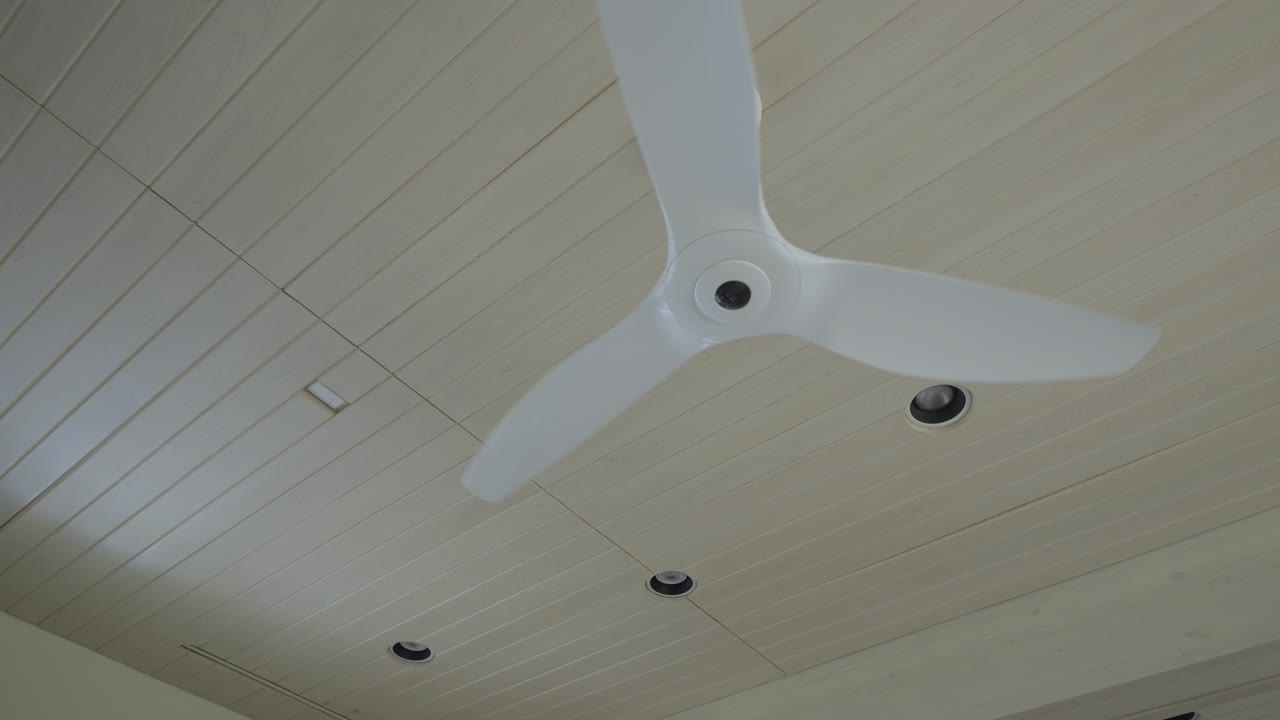 천장 팬은 흰색 나무 천장에 최면적으로 회전합니다.