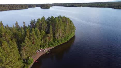 Drohnenaufnahme-Einer-Insel-Inmitten-Eines-Nördlichen-Sees-Mit-Einem-Kajak-Am-Ufer