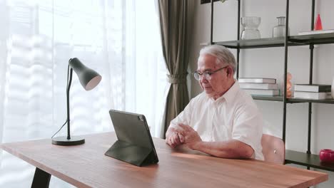 mature asian senior making video call through his digital tablet