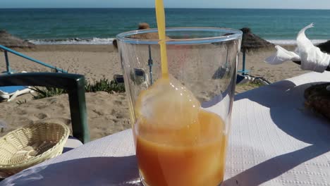 Gießen-Sie-Saft-In-Ein-Glas-Am-Strand-Mit-Meerblick,-Marbella,-Spanien