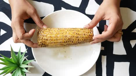 mujeres con una mazorca de maíz en un plato,