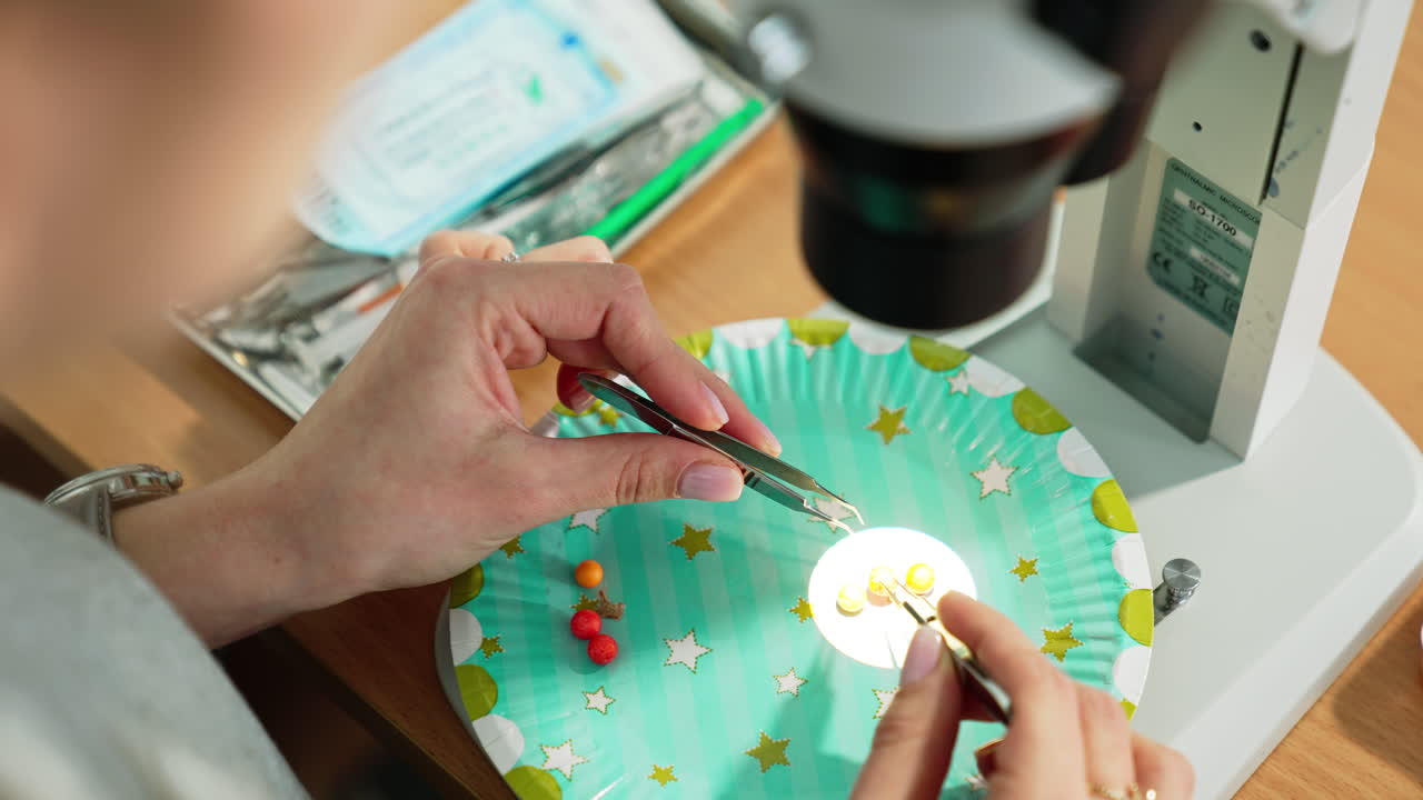 Female hands holding forceps and use them to move beads. Medical students studying ophthalmology course and practicing.