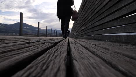 Tiro-De-ángulo-Bajo-De-Bloqueo-De-Una-Joven-Asiática-Caminando-Sobre-Un-Muelle-De-Madera-En-Cámara-Lenta