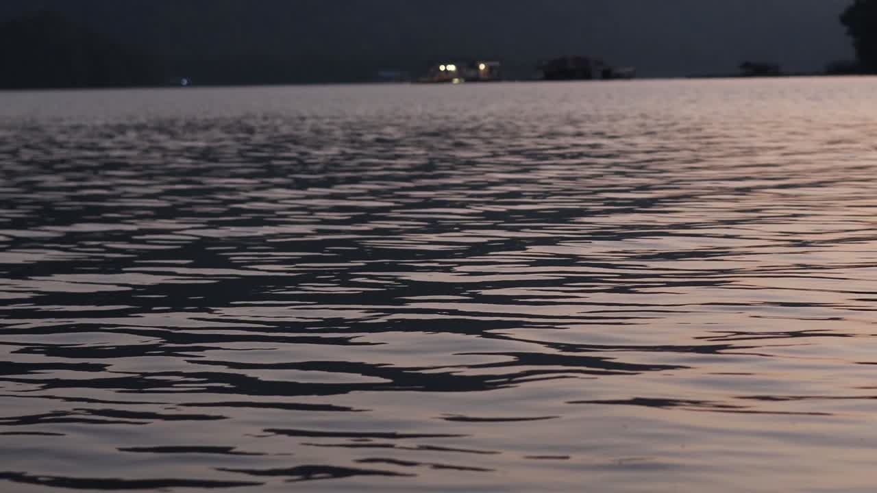 Gentle ripples on a tranquil lake reflect the soft hues of the evening sky.