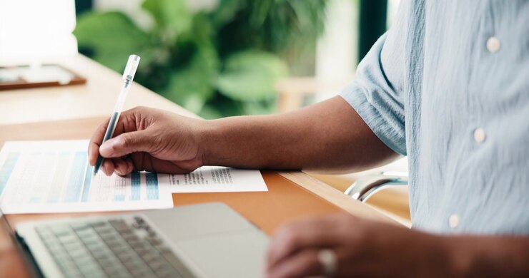 Professional Reviewing Financial Documents and Working on Laptop