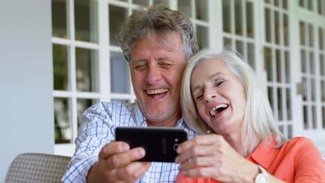Senior-couple-using-mobile-phone-on-the-porch-4k