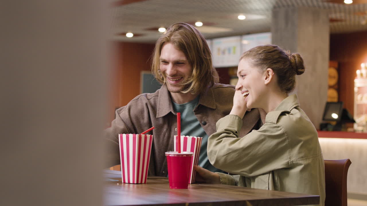 영화관 스낵바에서 팝콘을 먹으면서 스마트폰으로 셀카를 찍는 행복한 커플