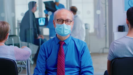 senior man looking at camera in hospital waiting area