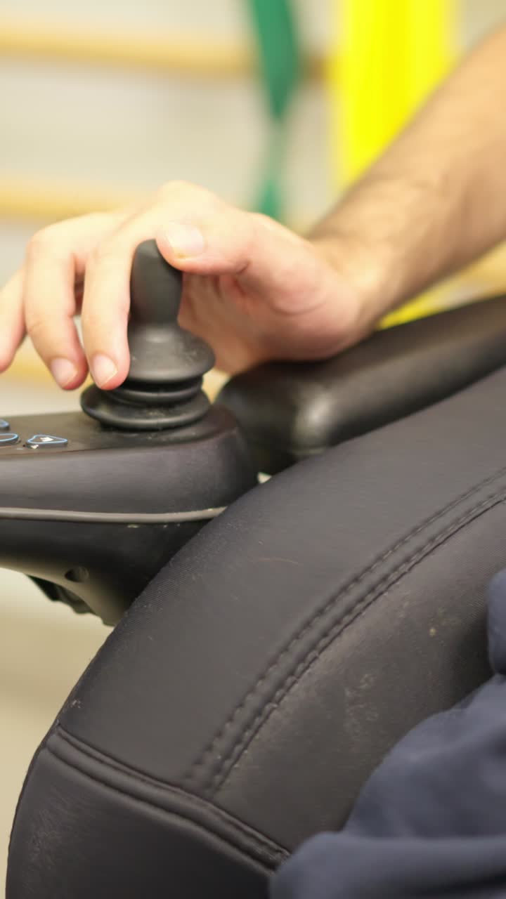 Primer plano de una mano manejando el joystick de una silla de ruedas eléctrica